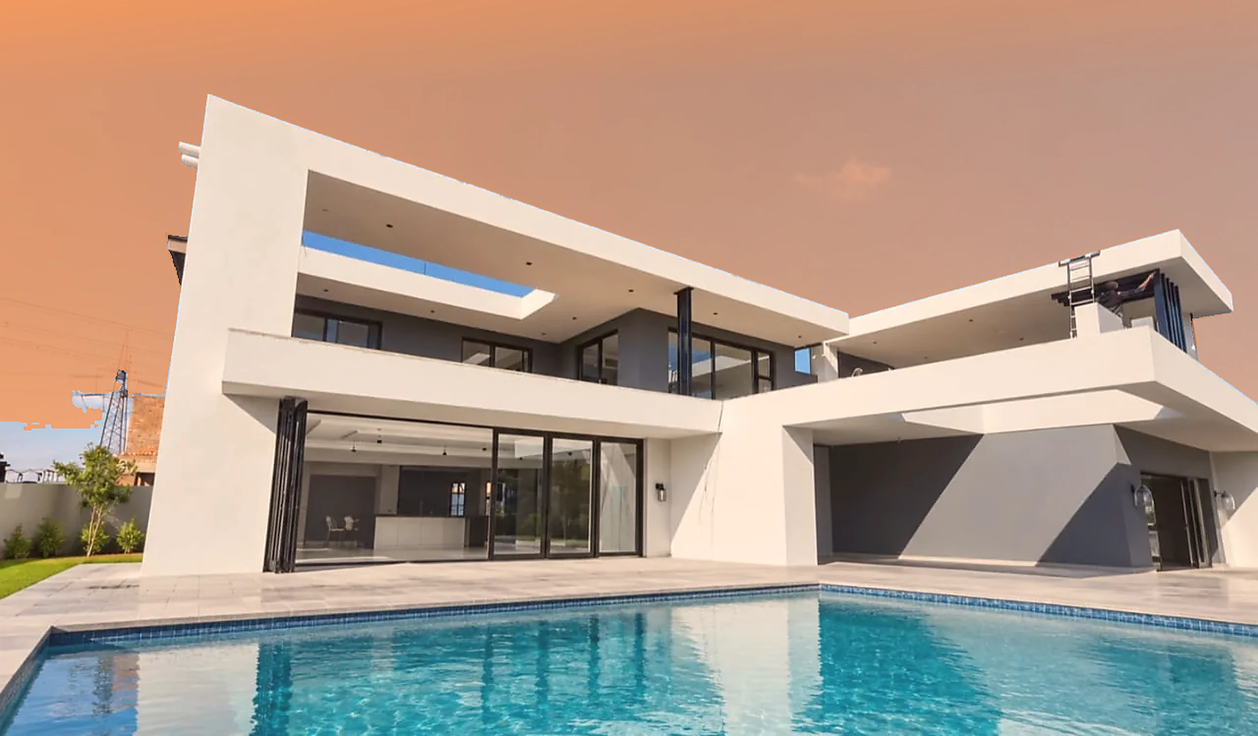 Sunset-toned view of a contemporary home with aluminium-framed glazing beside a pool